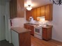 View of the kitchen with laminate counter tops, electric stove and oven, refrigerator and plenty of cabinets.